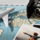 A imagem evoca a ideia de planejamento de um intercâmbio. O mapa-múndi sugere a escolha do destino, o avião simboliza a viagem, a câmera representa a vontade de registrar as memórias e as fotos ilustram a experiência em si, com a liberdade e a exploração de novos lugares. A composição remete à preparação e à expectativa que envolvem um intercâmbio, convidando o espectador a imaginar as possibilidades e a se inspirar para a própria jornada.