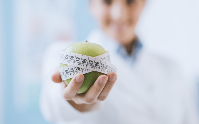 Nutricionista segura maçã verde com fita métrica, conceito de dieta e saúde.