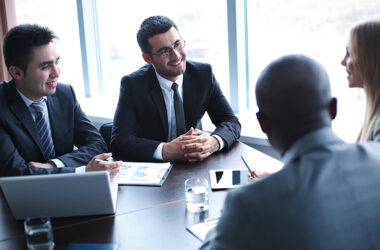 Comércio Exterior: Três homens e uma mulher em uma mesa de reunião em uma conversa de negócio