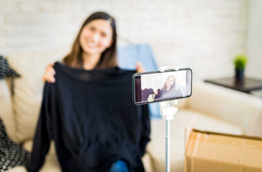 Menina da dicas de vídeo pelo celular mostra blusa preta e grava a cena com celular em primeiro plano
