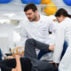 Estudantes de Fisioterapia realizam atendimento supervisionado na área de neurologia, auxiliando na reabilitação de paciente idoso.