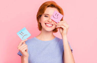 Áreas da psicologia com mulher segurando dois emojis um feliz e um triste