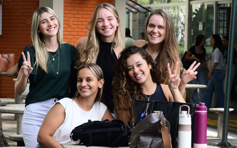 Grupo de estudantes da Unoeste reunidas no campus, sorrindo e interagindo em área de convivência.