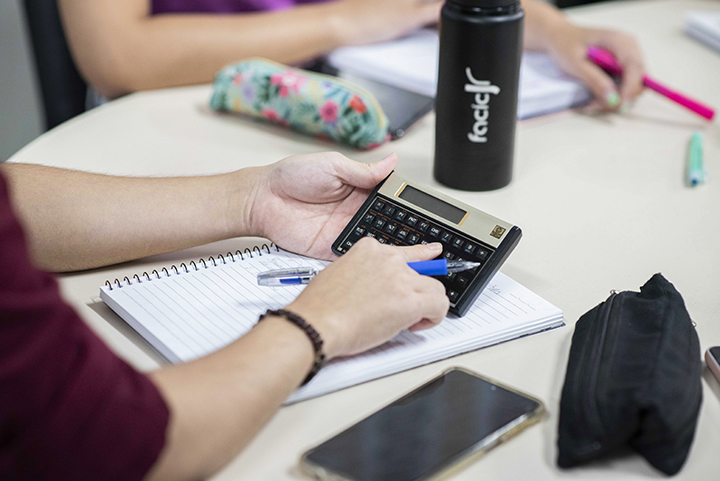 Jovem estudante utilizando uma calculadora no curso de Administração