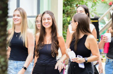 Grupo de jovens caminhando pelo campus universitário, representando estudantes explorando diferentes opções de formação como bacharelado, licenciatura e tecnólogo.