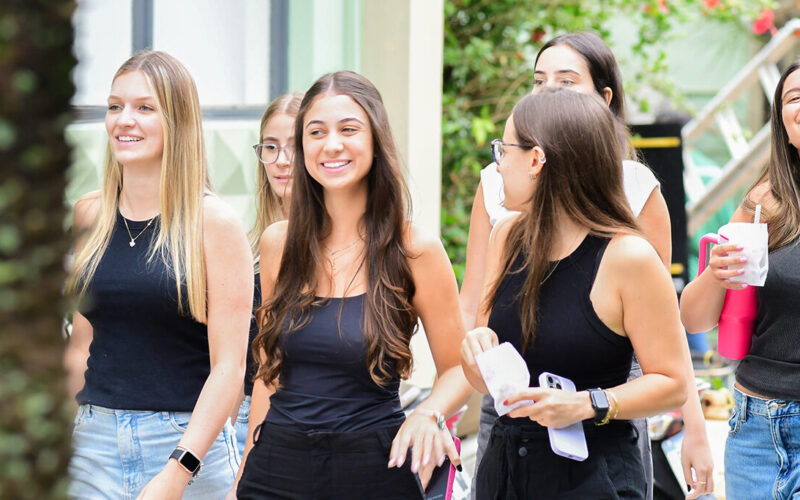 Grupo de jovens caminhando pelo campus universitário, representando estudantes explorando diferentes opções de formação como bacharelado, licenciatura e tecnólogo.