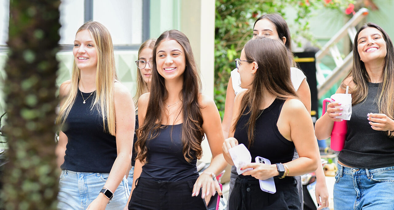 Grupo de jovens caminhando pelo campus universitário, representando estudantes explorando diferentes opções de formação como bacharelado, licenciatura e tecnólogo.