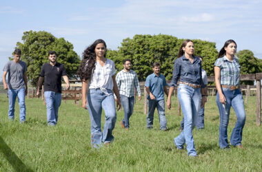 Profissionais do campo com jovens caminhando em uma pastagem