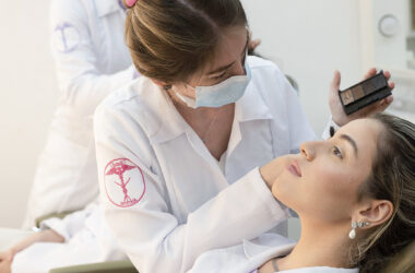 Estudante de Estética e Cosmética realizando procedimento de maquiagem facial em paciente durante atividade prática supervisionada, destacando técnicas profissionais de cuidado com a pele e embelezamento.