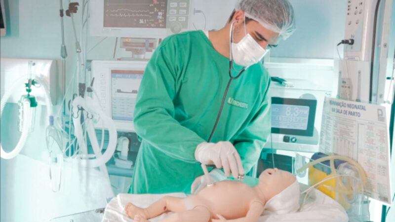 Aluno de Medicina da Unoeste utiliza um boneco ultrarrealista em laboratório de simulação para treinar procedimentos clínicos, demonstrando o uso de tecnologia na saúde na formação dos futuros profissionais.