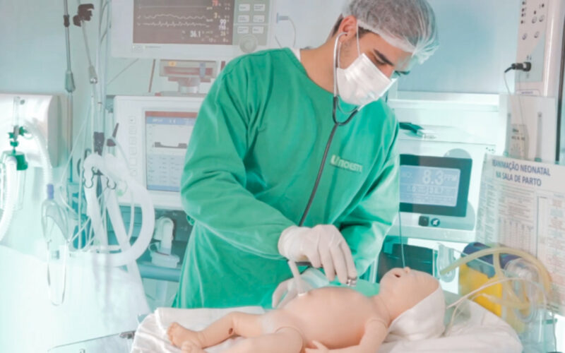 Aluno de Medicina da Unoeste utiliza um boneco ultrarrealista em laboratório de simulação para treinar procedimentos clínicos, demonstrando o uso de tecnologia na saúde na formação dos futuros profissionais.