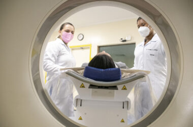 Saiba detalhes sobre como é o curso de Radiologia. Na foto, duas alunas em aula prática com uma paciente em exame de ressonância.
