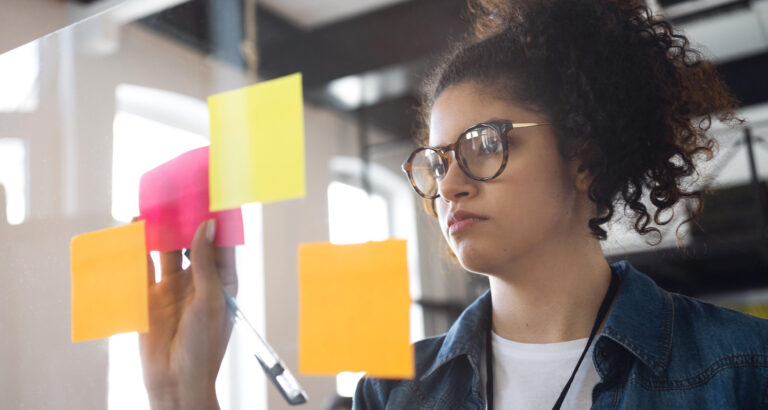 Estudante organizando ideias em notas adesivas coloridas durante atividade de planejamento e construção de mapa mental.