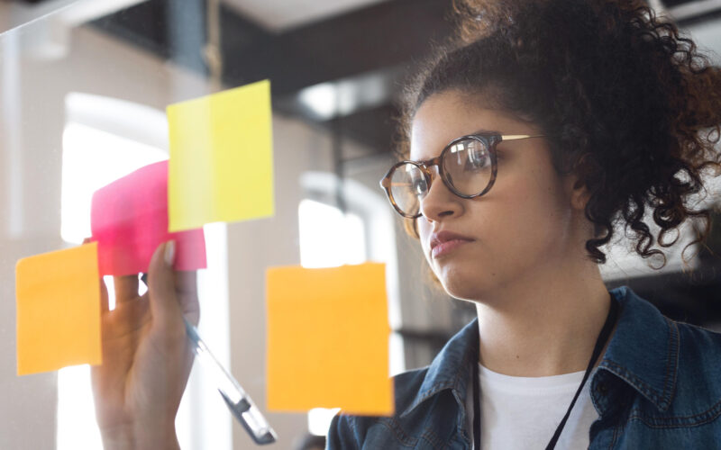 Estudante organizando ideias em notas adesivas coloridas durante atividade de planejamento e construção de mapa mental.