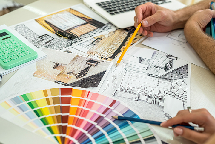 Saiba tudo o que faz um designer de interiores. Na foto, aparecem as mãos de dois jovens definindo cores para um projeto de designer de interior.