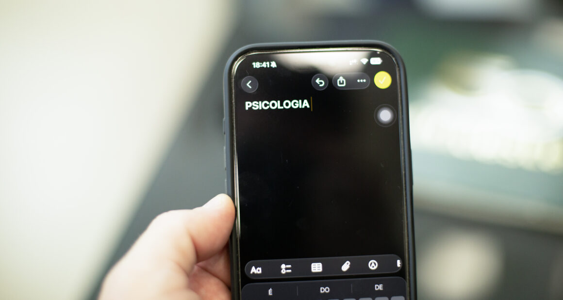 Pessoa segura um celular com a palavra “Psicologia” digitada na tela de um aplicativo de anotações.