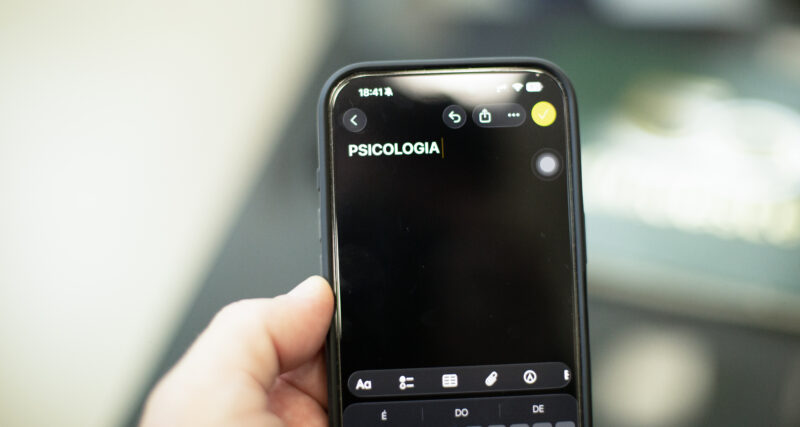 Pessoa segura um celular com a palavra “Psicologia” digitada na tela de um aplicativo de anotações.