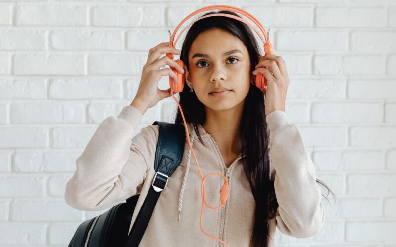 Adolescente usando fones de ouvido para escutar podcast de true crime. 