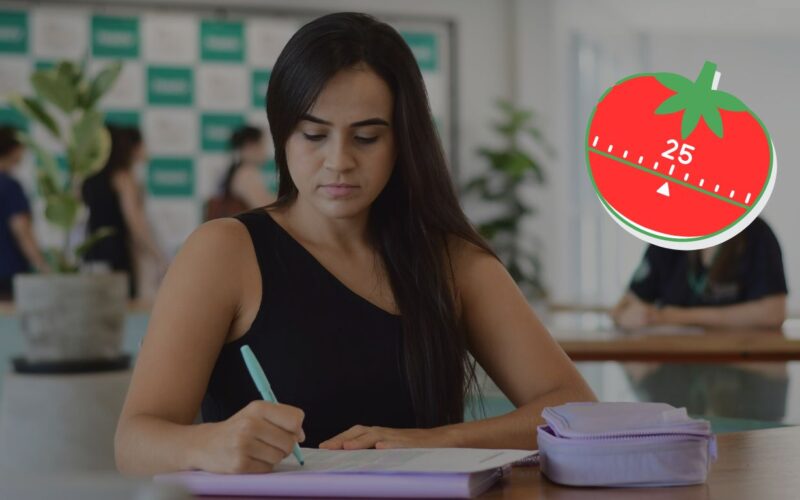 Na foto, uma estudante de graduação aplicando a técnica pomodoro para se concentrar e ser produtiva nos estudos. À direita, timer em formato de tomate marcando 25 minutos para representar a técnica pomodoro.