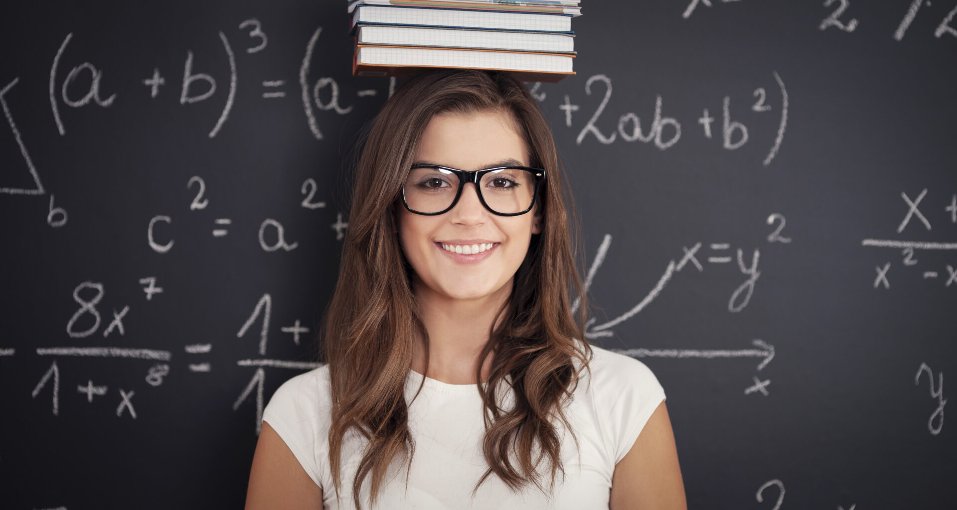 Aluna sorrindo e atrás quadro com cálculos de matemática para o Enem.