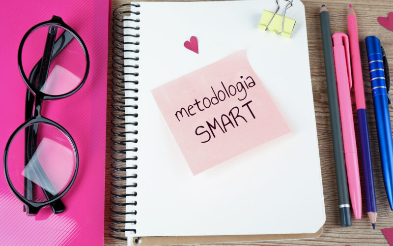 Caderno com anotação de” metodologia smart”, canetas, lápis e óculos.