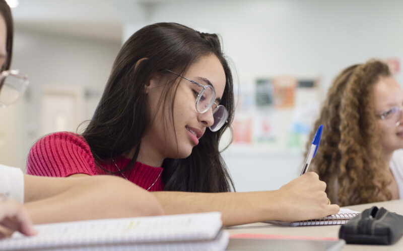 Jovem montando plano de carreira no caderno ao lado de suas amigas