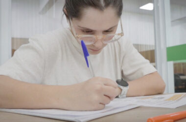 Estudante concentrada fazendo anotações em caderno durante os estudos para o Enem, com materiais de apoio e marca-texto sobre a mesa.