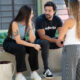 Três estudantes universitários conversam ao ar livre em área de convivência do campus, trocando experiências e discutindo sobre escolhas profissionais e a vida acadêmica.