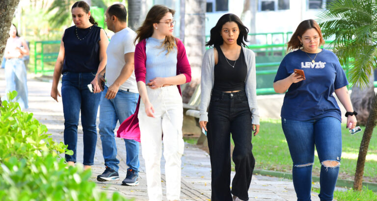 Grupo de pessoas caminhando ao ar livre pelo campus da universidade.