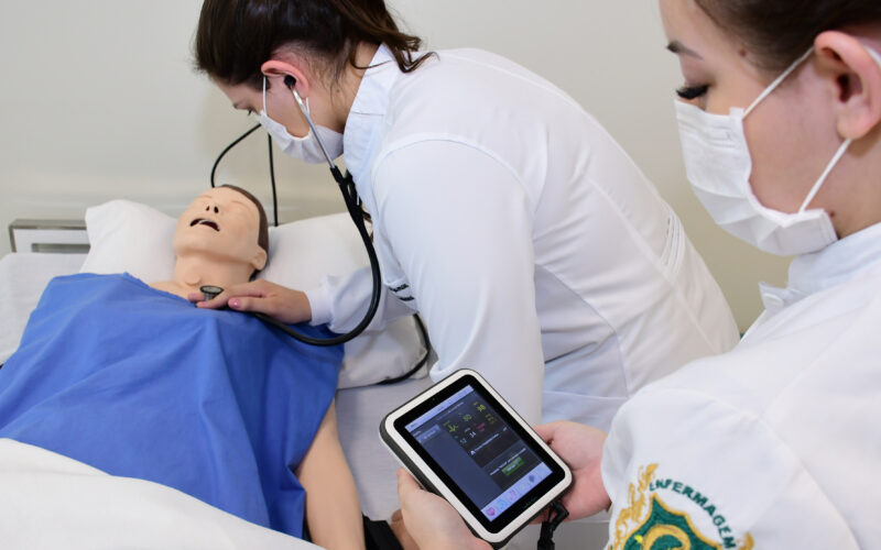 Estudantes de enfermagem realizando procedimento em boneco e simulando atendimento humano.