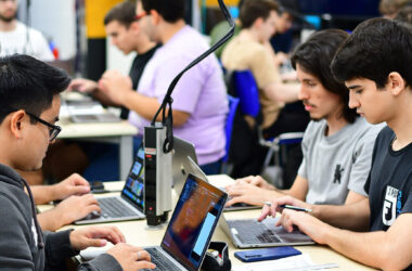 Estudantes do curso de Sistemas de Informação da Unoeste trabalhando em laboratório de informática, utilizando notebooks para atividades práticas de programação e desenvolvimento de sistemas.