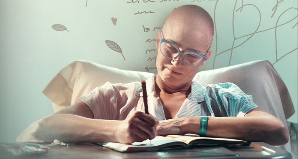 Imagem do filme 'Caderno de Tomy', mostrando a personagem principal escrevendo em um caderno enquanto está no hospital.