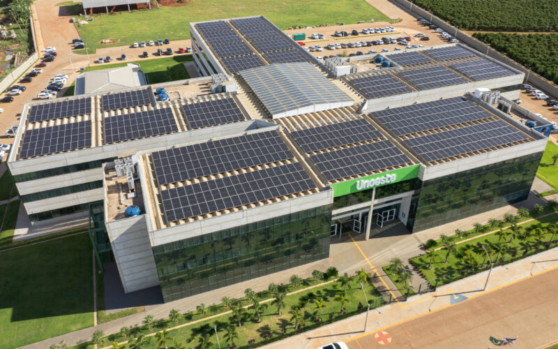 Imagem aérea do campus da Unoeste em Jaú, SP, destacando o prédio moderno com painéis solares no telhado, áreas verdes bem cuidadas ao redor e amplo estacionamento. Uma estrutura que reflete sustentabilidade e excelência acadêmica.
