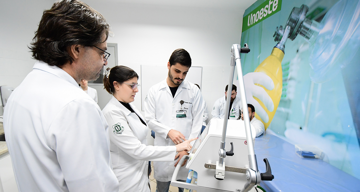 Estudantes de Medicina da Unoeste em aula prática, utilizando equipamentos modernos. A imagem destaca a infraestrutura de qualidade e o aprendizado na área da saúde.