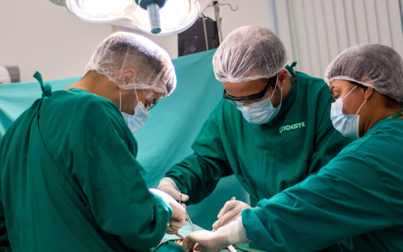 Alunos do curso de Medicina da Unoeste participando de uma aula prática em um laboratório de simulação cirúrgica, utilizando trajes e equipamentos adequados para procedimentos médicos.