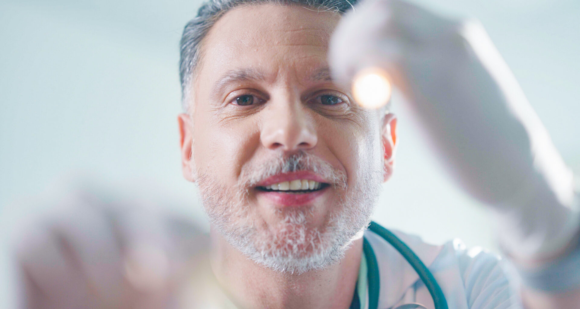 Médico realizando exame clínico com luz de diagnóstico. A evolução da medicina, dos tratamentos antigos às tecnologias modernas, transformou os cuidados com a saúde.