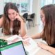 Estudantes universitárias em momento de estudo com livro aberto, representando uma rotina produtiva em ambiente acadêmico organizado.