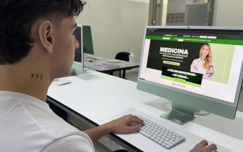 Estudante jovem acessa o site da Unoeste em um computador, visualizando informações sobre o Vestibular de Medicina. A imagem representa o interesse de adolescentes em começar a faculdade e buscar informações sobre vestibulares.