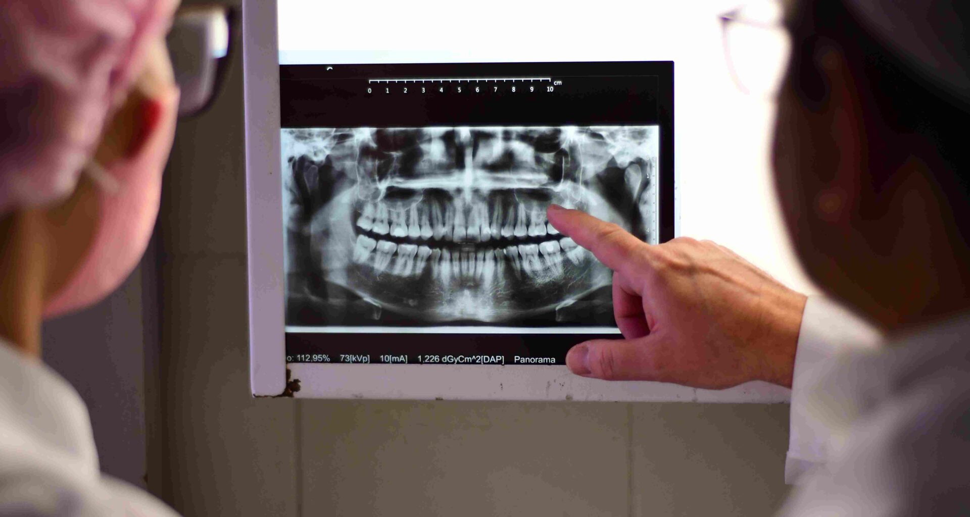 Professor e estudantes de Odontologia da Unoeste analisam radiografia panorâmica dos dentes durante aula prática em clínica odontológica da universidade.