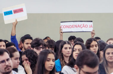 Público assiste simulação de julgamento com cartazes “Crime brutal” e “Condenação já” erguidos por participantes, em atividade acadêmica do curso de Direito da Unoeste.