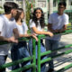 Quatro estudantes universitários conversam ao ar livre no campus da Unoeste, cercados por palmeiras e edifícios modernos, vestindo camisetas brancas e calças jeans, em um ambiente descontraído e acolhedor.