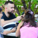 Grupo de jovens conversando ao ar livre no campus da Unoeste, representando a importância da saúde social, mental e emocional. Na cena, uma jovem de blusa cinza está à esquerda, um rapaz de barba usa camiseta preta, outra jovem de blusa rosa e calça jeans está de costas, e um rapaz de óculos veste camiseta verde escura.