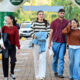 Estudantes caminham juntos pelo campus da Unoeste, em área externa sinalizada com bandeiras da universidade.