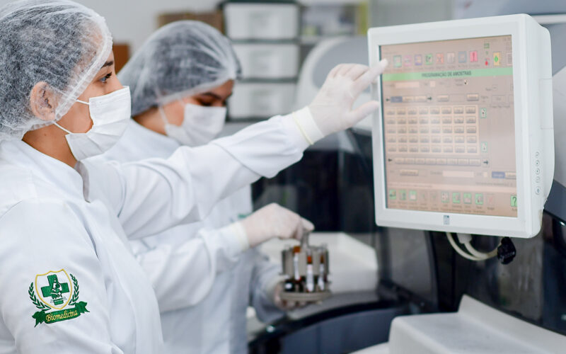 Estudantes de Biomedicina realizando análises em laboratório com equipamentos modernos durante prática acadêmica.