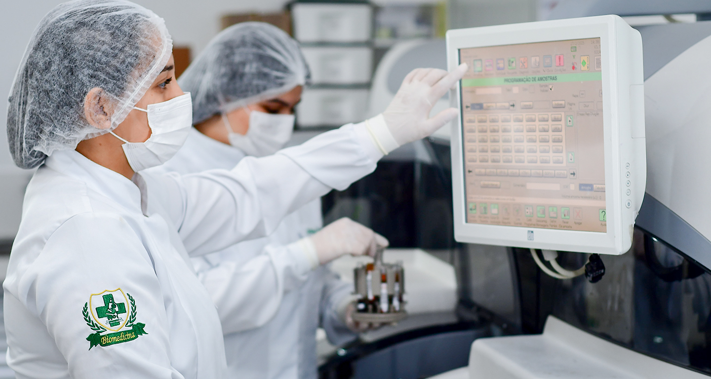 Estudantes de Biomedicina realizando análises em laboratório com equipamentos modernos durante prática acadêmica.