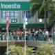 Dia de ENEM na Unoeste: Estudantes caminham em passarela verde em frente ao Bloco B3 da universidade, com palmeiras e postes de luz ao redor.