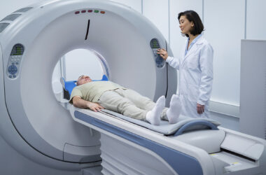 Paciente realiza exame de PET-CT em aparelho de Medicina Nuclear com acompanhamento de profissional de saúde.
