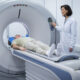 Paciente realiza exame de PET-CT em aparelho de Medicina Nuclear com acompanhamento de profissional de saúde.
