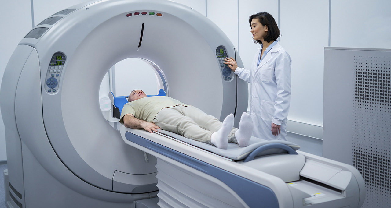 Paciente realiza exame de PET-CT em aparelho de Medicina Nuclear com acompanhamento de profissional de saúde.
