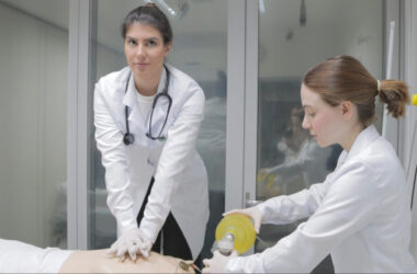 Duas estudantes de Medicina da Unoeste realizam treinamento prático em laboratório: uma executa massagem cardíaca em manequim de simulação, enquanto a outra auxilia com ventilação manual, representando a atuação das mulheres na Medicina.